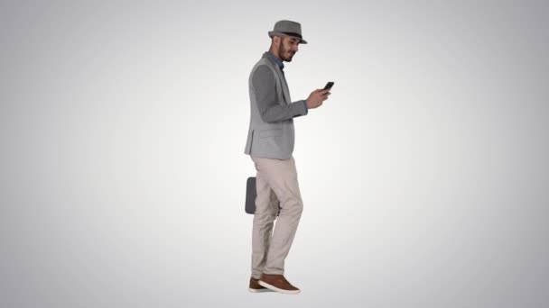 Nenucený muž textování na telefonu a chůze na gradient pozadí. — Stock video