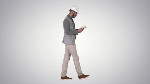 Joven arquitecto leyendo libro de texto o cuaderno mientras camina sobre fondo degradado . — Vídeo de stock