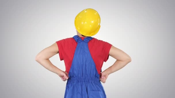 Женщина-строитель с руками на бедрах смотрит на что-то на градиентном фоне . — стоковое видео