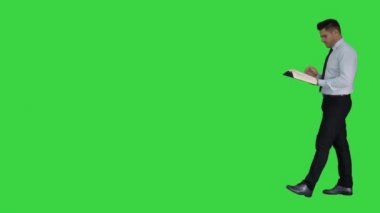 Genç karışık adam yeşil ekran üzerinde yürürken akıllı kitap yanlış anlama içeriği okumaya çalışırken, Chroma anahtar.
