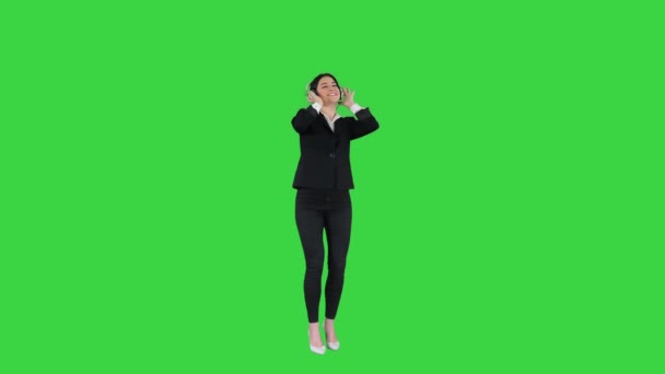 Молодая деловая женщина слушает музыку в наушниках и танцует на зеленом экране, Chroma Key. — стоковое видео