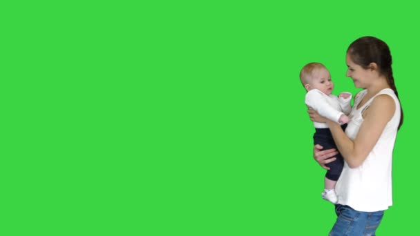 Joven madre sosteniendo a su bebé en las manos y caminando en una pantalla verde, Chroma Key . — Vídeos de Stock
