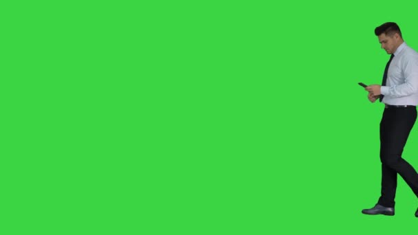 Man walking looking on phone and making win gesture on a Green Screen, Chroma Key. — Stock Video