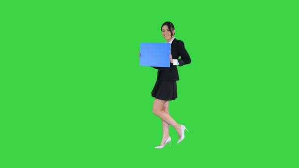 Linda chica sosteniendo tablero vacío anunciando o presentando algo en una pantalla verde, maqueta azul . — Vídeo de stock