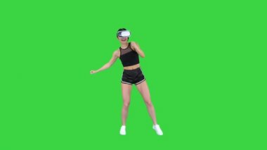Mutlu gülümseyen genç kız kullanarak VR kulaklık gözlük oynarken dans oyunu Ilk kez yeşil ekran, Chroma anahtar.