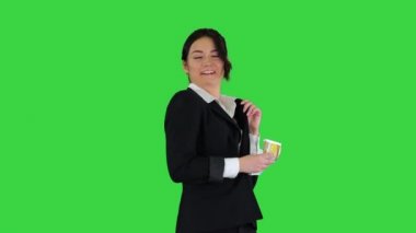 Kendinden emin ve mutlu genç iş kadını cebine para koyup yeşil ekranda dans ediyor, Chroma Key..