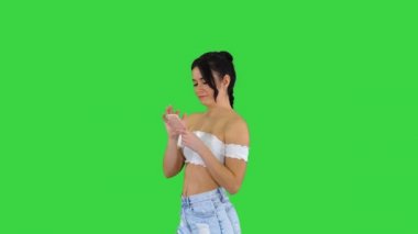 Cep telefonunu kontrol eden ve yeşil ekranda dans eden tatlı bir kız, Chroma Key..