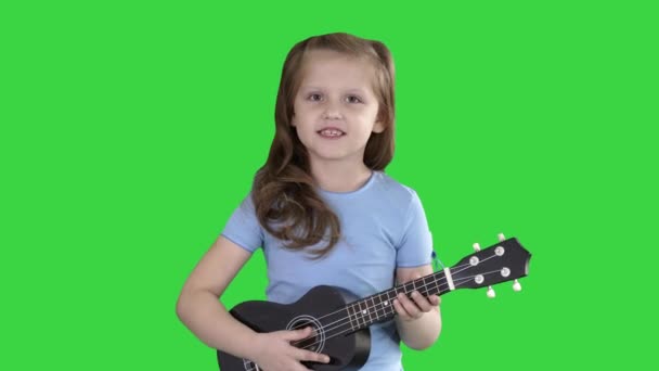 Menina cantando e tocando guitarra pequena enquanto caminha em direção à câmera em uma tela verde, Chroma Key . — Vídeo de Stock