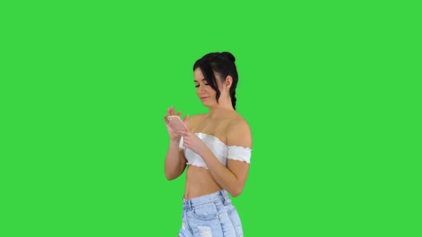 Linda chica revisando su teléfono celular y bailando en una pantalla verde, Chroma Key. — Vídeo de stock