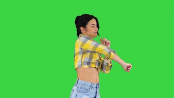 Дівчинка в квадратній сорочці і джинсах шорти, кросівки, танцює на зеленому екрані, Chroma Key. — стокове відео