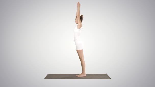 Hermosa joven haciendo ejercicio de yoga para tobillos, pantorrillas, muslos, caderas y hombros, Eagle Pose, Garudasana sobre fondo degradado . — Vídeos de Stock