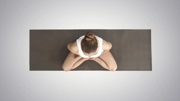 Donna in bianco praticare yoga in posa loto su sfondo sfumato . — Video Stock