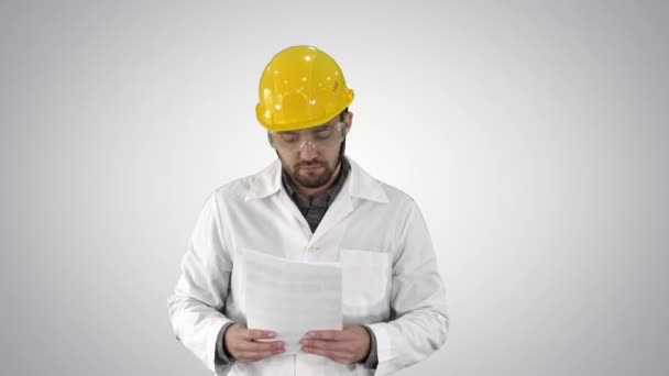 Site engineer cheching papers and something around him on gradient background. — Stock Video