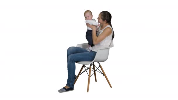 Madre y lindo bebé sentado en una silla sobre fondo blanco . — Vídeo de stock