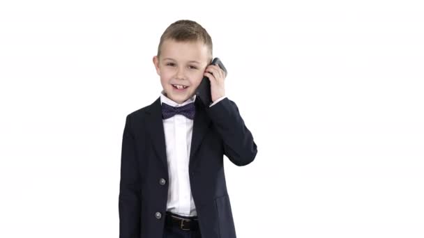 Malý chlapec v kostýmu, který si při chůzi na bílém pozadí zatelefonoval. — Stock video