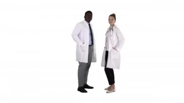 Beyaz arka planda kamera arıyor ayakta iki Kafkas ve Afro Amerikan gülümseyen doktorlar.