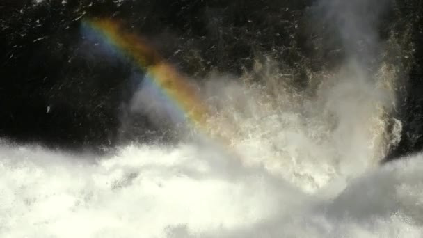 Rainbow over the running water of the waterfall. — Stock Video