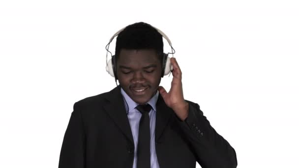 Guapo afroamericano hombre de negocios en auriculares está escuchando música sobre fondo blanco. — Vídeo de stock