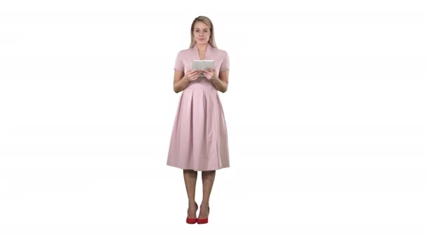 Довольно очаровательная уверенная в себе модная женщина в розовом с планшетом в руках, смотрящая в камеру и переворачивая страницы или рыгая кнопки на вкладке на белом фоне. — стоковое видео