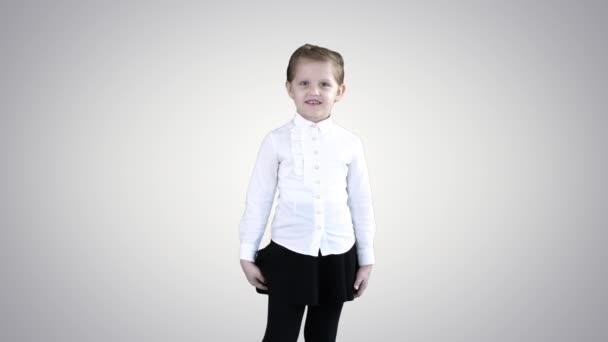 Ευτυχισμένο χαριτωμένο μικρό κορίτσι περπατάει στο πλαίσιο και μιλάει με την κάμερα στο φόντο ντεγκραντέ. — Αρχείο Βίντεο
