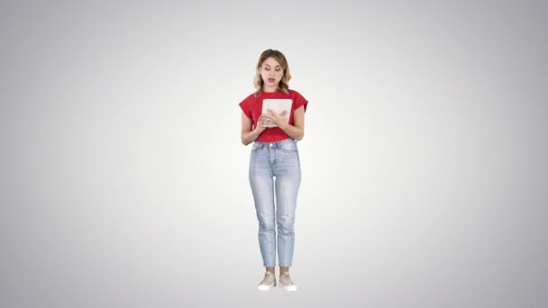 Mujer leyendo en la tableta y hablando con la cámara en el fondo gradiente . — Vídeo de stock