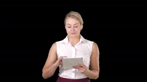 Güzel bir kız elinde tablet dokunmatik bilgisayarla sayfaları karıştırıyor ve kameraya bakıyor, Alfa Kanalı. — Stok video