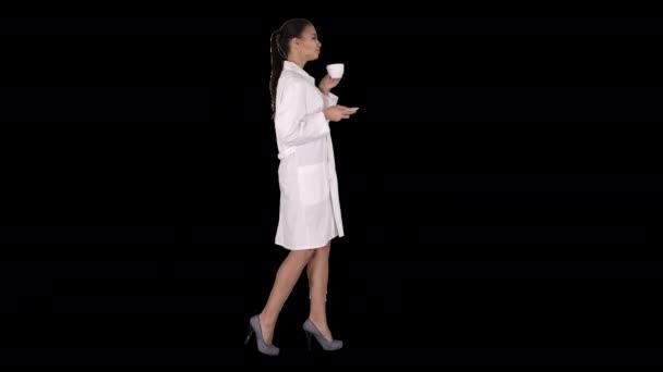 Young nurse relaxing drinking coffee or tea while walking, Alpha Channel — Stock Video