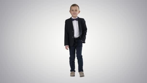 Niño en traje formal caminando con una mano en el bolsillo sobre fondo degradado . — Vídeo de stock