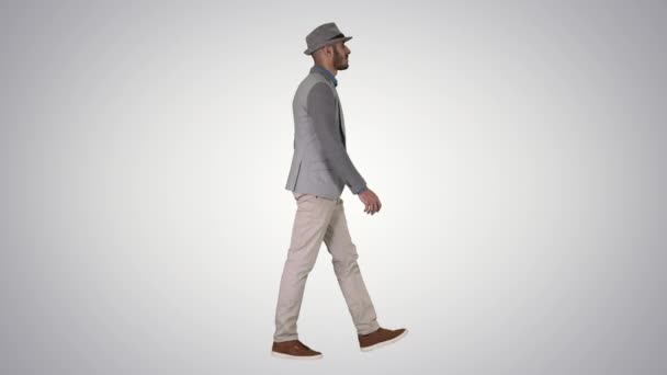 Occasionnel arabe homme en chapeau marchant sur fond de dégradé. — Video