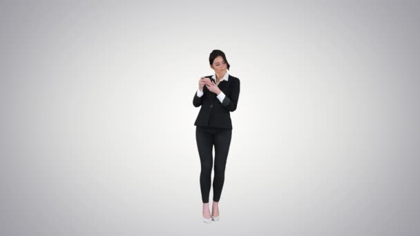 Mladá obchodní žena naslouchající hudbě na telefonu a tančí na pozadí gradientu. — Stock video