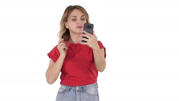 Eine nette junge Frau glättet ihre Haare und schaut in das Handy auf weißem Hintergrund. — Stockvideo