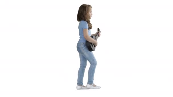 Uma menina caminhando com ukulele nas mãos sobre fundo branco . — Vídeo de Stock