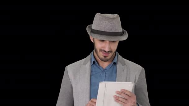 Charmant homme arabe souriant dans un chapeau marchant et utilisant une tablette, Alpha Channel — Video