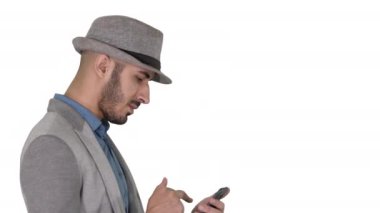 Beyaz arka planda yürürken akıllı telefon kullanan ciddi bir Arap adam..