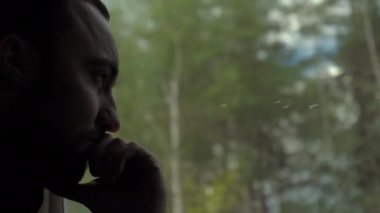 Pencereden bakan bir adam, trende çenesi olan, ciddi bir ifade..