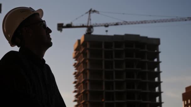 Silhouette constructeur ingénieur porter casque de sécurité regard sur la construction de papier de plan et de fumer. — Video