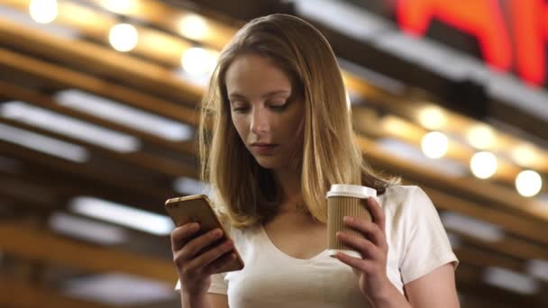 Ocupada joven mujer mensajes de texto en su teléfono celular y beber café. — Vídeos de Stock