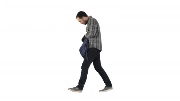 Joven estudiante masculino caminando sobre fondo verde aislado con bolsa y teléfono móvil sobre fondo blanco . — Vídeos de Stock