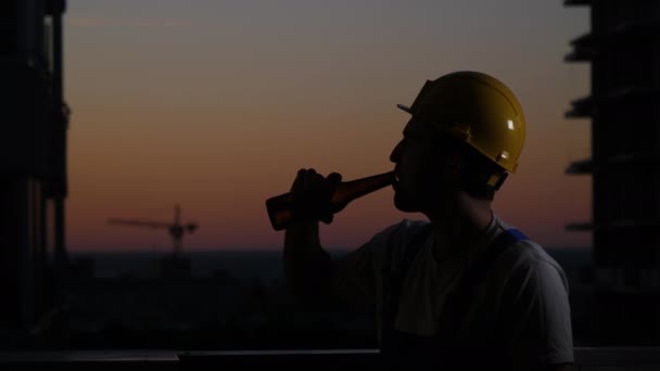 Bauarbeiter trinkt Bier im Helm. — Stockvideo