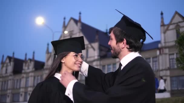 幸せな卒業生のカップルがお互いを見て. — ストック動画