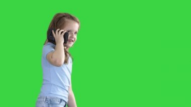 Küçük kız konuşmak telefon ve Yeşil Ekranda yürüyüş, Chroma Anahtar.