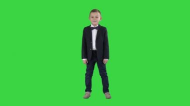 Yeşil Ekranda duran resmi kıyafetler içinde gülümseyen küçük çocuk, Chroma Key.