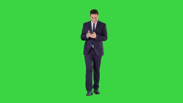 Empresario en el teléfono escribiendo mensaje de texto caminando en una pantalla verde, Chroma Key . — Vídeo de stock