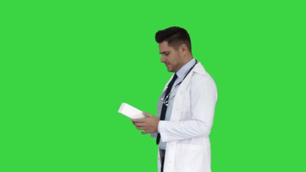 グリーンスクリーン、クロマキーの箱に新しい錠剤を記述ホワイトコートの成熟した医師. — ストック動画