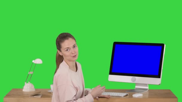 Charming woman presenting something on the screen of computer talking to camera Blue Screen Mock-up Display on a Green Screen, Chroma Key. — Stock Video