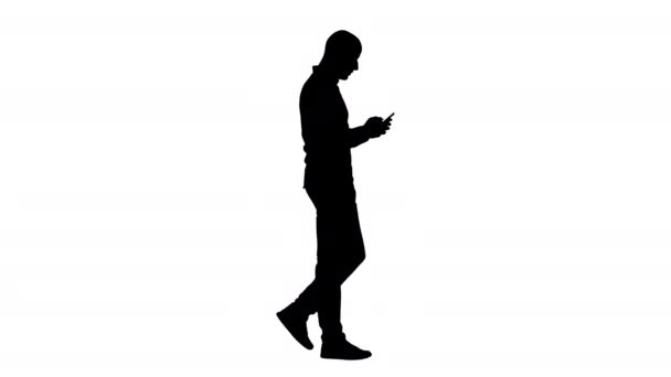 Sylwetka Młody człowiek spaceruje i korzysta z telefonu. — Wideo stockowe