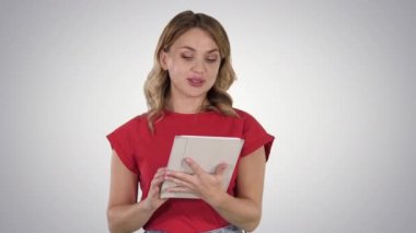 Kırmızı tutan tablet sarışın kadın ve degrade arka planda ondan kameraya okuma.