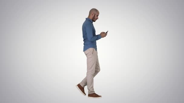 Jongeman lopen en met behulp van een telefoon op gradiënt achtergrond. — Stockvideo