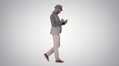 Degrade arka planda yürürken akıllı telefon kullanarak ciddi Arapça rahat adam.