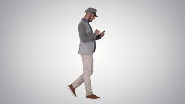 Serious arabic casual man using smartphone while walking on gradient background. — Stock Video